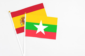 Myanmar and Spain stick flags on white background. High quality fabric, miniature national flag. Peaceful global concept.White floor for copy space.