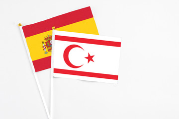 Northern Cyprus and Spain stick flags on white background. High quality fabric, miniature national flag. Peaceful global concept.White floor for copy space.
