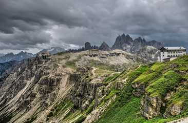 Storm clouds over Dolomites mountains and alpine hut.  Travel Italy. Scenic view from Tre Cime towards a mountain hut. South Tyrol. Italy.
