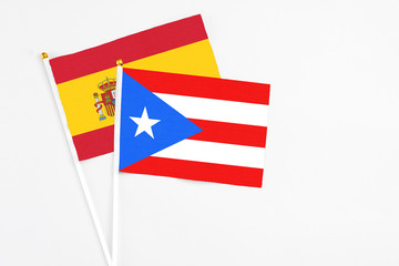 Puerto Rico and Spain stick flags on white background. High quality fabric, miniature national flag. Peaceful global concept.White floor for copy space.