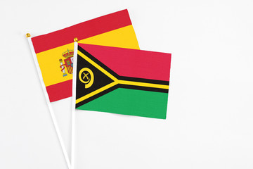Vanuatu and Spain stick flags on white background. High quality fabric, miniature national flag. Peaceful global concept.White floor for copy space.