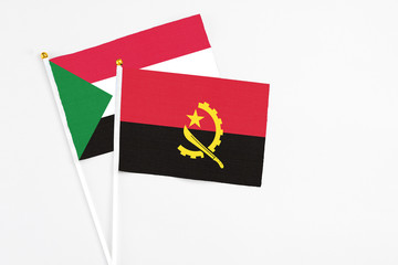 Angola and Sudan stick flags on white background. High quality fabric, miniature national flag. Peaceful global concept.White floor for copy space.