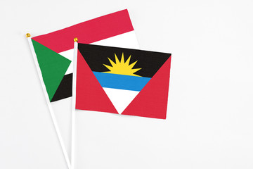 Antigua and Barbuda and Sudan stick flags on white background. High quality fabric, miniature national flag. Peaceful global concept.White floor for copy space.