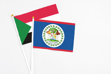 Belize and Sudan stick flags on white background. High quality fabric, miniature national flag. Peaceful global concept.White floor for copy space.