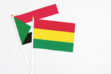 Bolivia and Sudan stick flags on white background. High quality fabric, miniature national flag. Peaceful global concept.White floor for copy space.