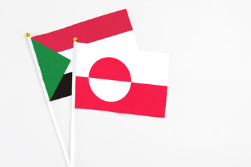 Greenland and Sudan stick flags on white background. High quality fabric, miniature national flag. Peaceful global concept.White floor for copy space.