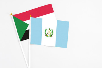 Guatemala and Sudan stick flags on white background. High quality fabric, miniature national flag. Peaceful global concept.White floor for copy space.
