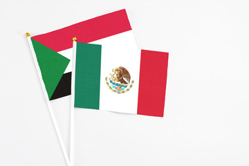 Mexico and Sudan stick flags on white background. High quality fabric, miniature national flag. Peaceful global concept.White floor for copy space.