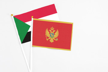 Montenegro and Sudan stick flags on white background. High quality fabric, miniature national flag. Peaceful global concept.White floor for copy space.