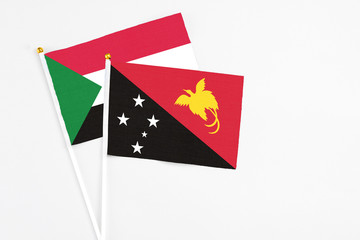 Papua New Guinea and Sudan stick flags on white background. High quality fabric, miniature national flag. Peaceful global concept.White floor for copy space.
