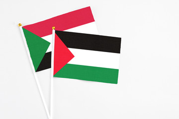 Palestine and Sudan stick flags on white background. High quality fabric, miniature national flag. Peaceful global concept.White floor for copy space.