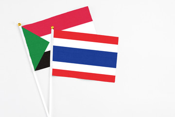Thailand and Sudan stick flags on white background. High quality fabric, miniature national flag. Peaceful global concept.White floor for copy space.