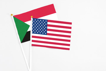 United States and Sudan stick flags on white background. High quality fabric, miniature national flag. Peaceful global concept.White floor for copy space.