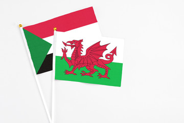 Wales and Sudan stick flags on white background. High quality fabric, miniature national flag. Peaceful global concept.White floor for copy space.