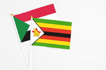Zimbabwe and Sudan stick flags on white background. High quality fabric, miniature national flag. Peaceful global concept.White floor for copy space.