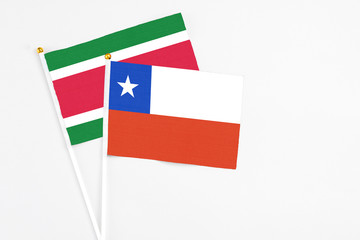 Chile and Suriname stick flags on white background. High quality fabric, miniature national flag. Peaceful global concept.White floor for copy space.