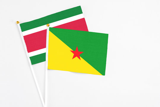 French Guiana and Suriname stick flags on white background. High quality fabric, miniature national flag. Peaceful global concept.White floor for copy space.