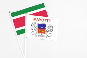 Mayotte and Suriname stick flags on white background. High quality fabric, miniature national flag. Peaceful global concept.White floor for copy space.
