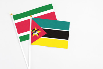Mozambique and Suriname stick flags on white background. High quality fabric, miniature national flag. Peaceful global concept.White floor for copy space.
