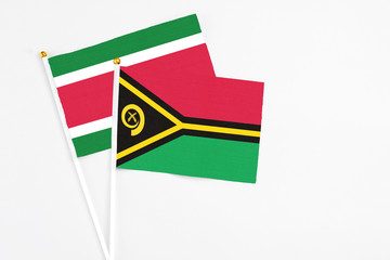 Vanuatu and Suriname stick flags on white background. High quality fabric, miniature national flag. Peaceful global concept.White floor for copy space.