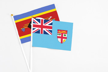 Fototapeta premium Fiji and Swaziland stick flags on white background. High quality fabric, miniature national flag. Peaceful global concept.White floor for copy space.
