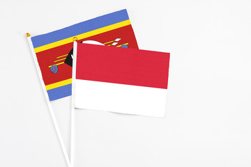 Monaco and Swaziland stick flags on white background. High quality fabric, miniature national flag. Peaceful global concept.White floor for copy space.