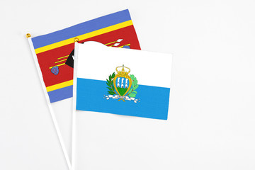 San Marino and Swaziland stick flags on white background. High quality fabric, miniature national flag. Peaceful global concept.White floor for copy space.