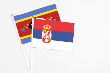 Serbia and Swaziland stick flags on white background. High quality fabric, miniature national flag. Peaceful global concept.White floor for copy space.