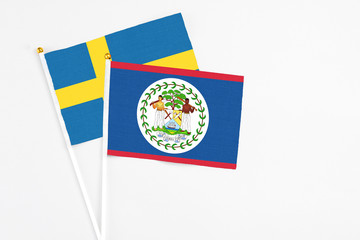 Belize and Sweden stick flags on white background. High quality fabric, miniature national flag. Peaceful global concept.White floor for copy space.