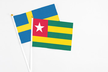 Togo and Sweden stick flags on white background. High quality fabric, miniature national flag. Peaceful global concept.White floor for copy space.