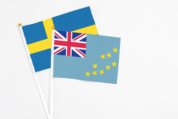 Fototapeta premium Tuvalu and Sweden stick flags on white background. High quality fabric, miniature national flag. Peaceful global concept.White floor for copy space.