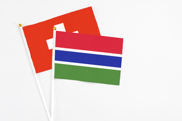 Gambia and Switzerland stick flags on white background. High quality fabric, miniature national flag. Peaceful global concept.White floor for copy space.