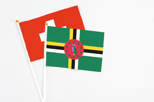 Dominica and Switzerland stick flags on white background. High quality fabric, miniature national flag. Peaceful global concept.White floor for copy space.