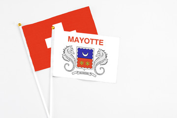 Mayotte and Switzerland stick flags on white background. High quality fabric, miniature national flag. Peaceful global concept.White floor for copy space.