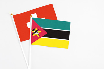 Mozambique and Switzerland stick flags on white background. High quality fabric, miniature national flag. Peaceful global concept.White floor for copy space.