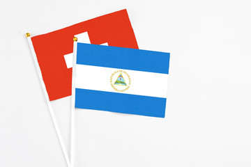 Nicaragua and Switzerland stick flags on white background. High quality fabric, miniature national flag. Peaceful global concept.White floor for copy space.