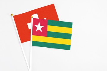 Fototapeta premium Togo and Switzerland stick flags on white background. High quality fabric, miniature national flag. Peaceful global concept.White floor for copy space.