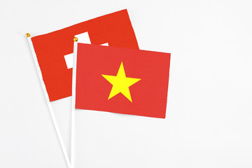 Vietnam and Switzerland stick flags on white background. High quality fabric, miniature national flag. Peaceful global concept.White floor for copy space.