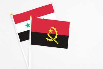 Angola and Syria stick flags on white background. High quality fabric, miniature national flag. Peaceful global concept.White floor for copy space.