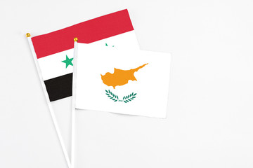 Cyprus and Syria stick flags on white background. High quality fabric, miniature national flag. Peaceful global concept.White floor for copy space.