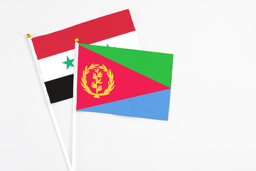 Eritrea and Syria stick flags on white background. High quality fabric, miniature national flag. Peaceful global concept.White floor for copy space.
