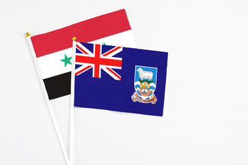 Fototapeta premium Falkland Islands and Syria stick flags on white background. High quality fabric, miniature national flag. Peaceful global concept.White floor for copy space.