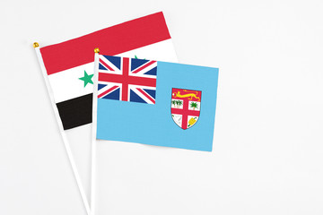 Fototapeta premium Fiji and Syria stick flags on white background. High quality fabric, miniature national flag. Peaceful global concept.White floor for copy space.