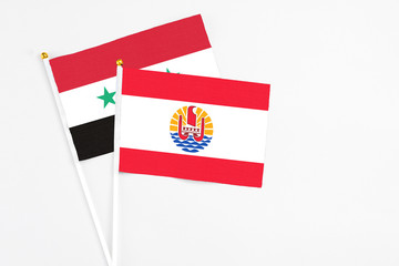 French Polynesia and Syria stick flags on white background. High quality fabric, miniature national flag. Peaceful global concept.White floor for copy space.