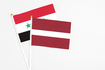 Latvia and Syria stick flags on white background. High quality fabric, miniature national flag....