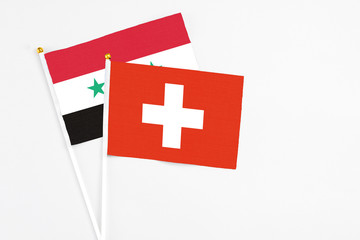 Obraz premium Switzerland and Syria stick flags on white background. High quality fabric, miniature national flag. Peaceful global concept.White floor for copy space.