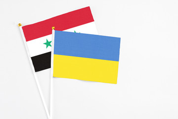 Ukraine and Syria stick flags on white background. High quality fabric, miniature national flag....