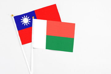 Madagascar and Taiwan stick flags on white background. High quality fabric, miniature national flag. Peaceful global concept.White floor for copy space.