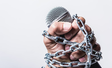 Hand holding microphone and have chain on fist hand on white background, Human rights day concept