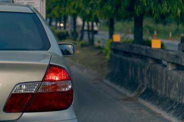 Naklejka premium Brake of gold car on the road stop by traffic condition. beside with tree and wall of bridge.